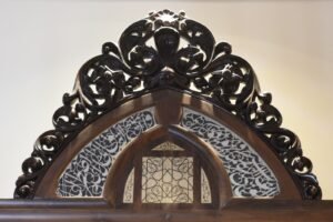 تاج المكتبة الموجودة في ردهة الصالون البطريركي وفي وسط الشمسة عبارة عبده النحات